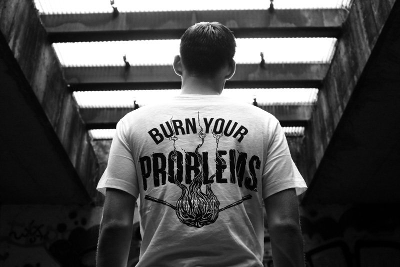 Ragazzo di spalle con maglietta con scritta "Burn your Problems"